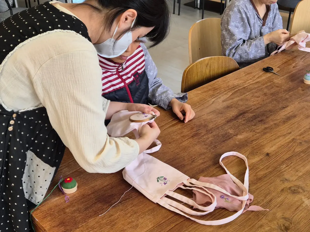 강사가 미니 토트백 자수를 1:1로 지도하는 모습