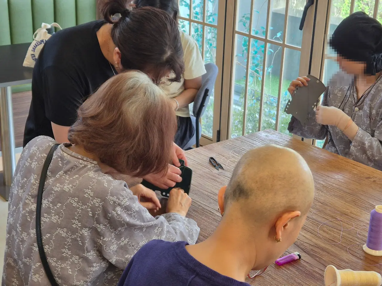 강사가 가죽 지갑 바느질을 1:1로 도와주는 모습