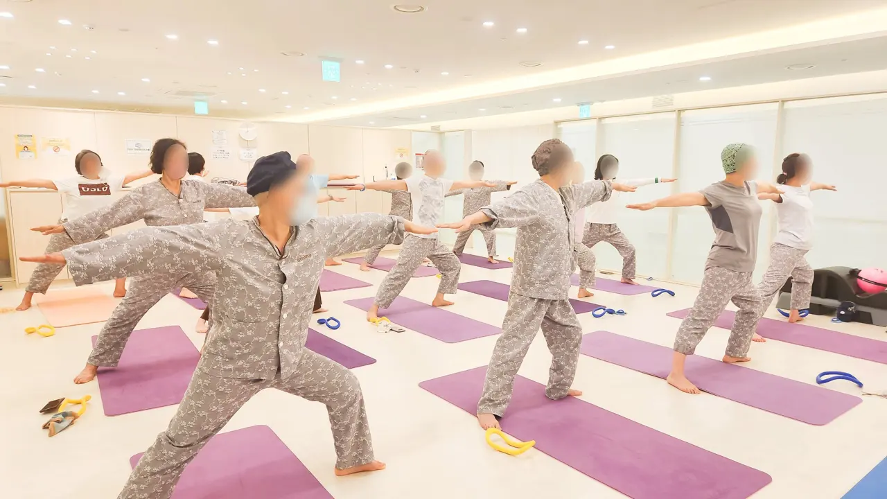 GX룸에서 팔을 넓게 펴고 스트레칭하는 환우들